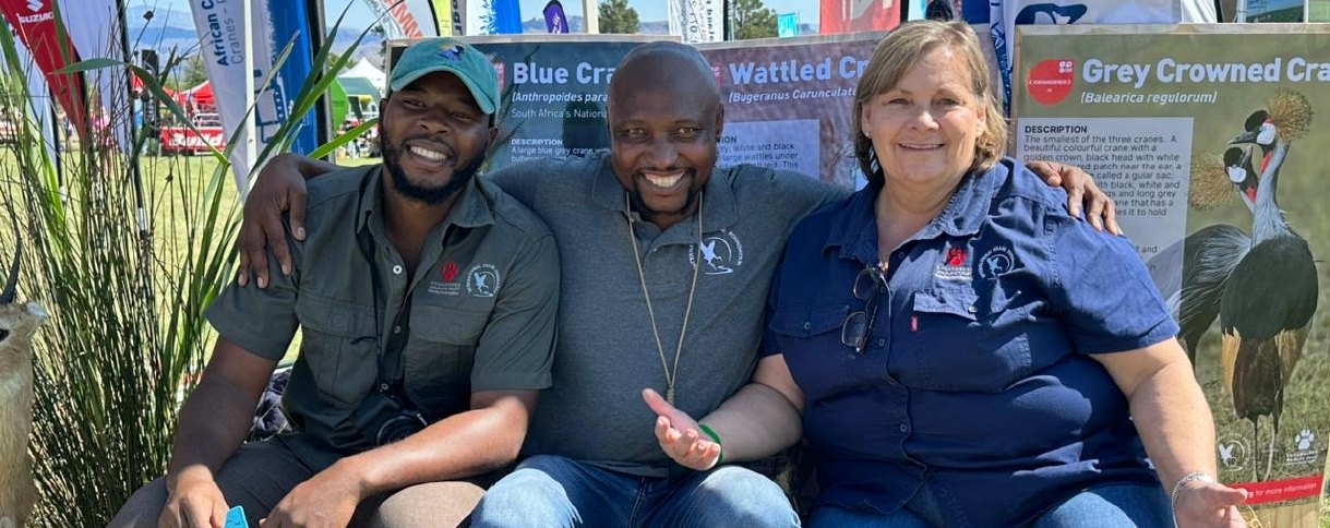 Three EWT team members in front of crane conservation display banners